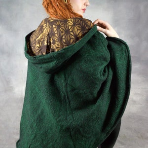 Puede incluir: Un poncho verde oscuro con capucha y forro estampado en dorado y marr&oacute;n. El poncho est&aacute; hecho de una tela suave y texturizada y tiene un corte holgado.