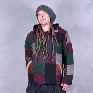 May include: A multi-coloured patchwork zip-up hooded jacket with a full-length zip and two front pockets. The jacket features squares of green, brown, black, and burgundy. The person in the image is wearing a grey beanie.