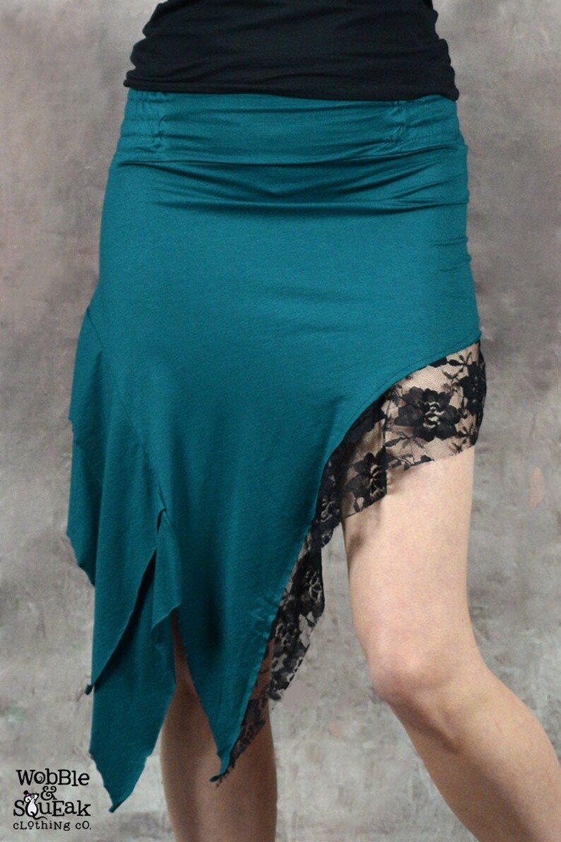 May include: A teal blue asymmetrical skirt with a black lace trim. The skirt is made of a soft, stretchy fabric and has a relaxed fit.