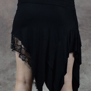 May include: Black asymmetrical skirt with a lace trim. The skirt is made of a soft, stretchy fabric and has a flowing, bohemian style.