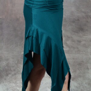 May include: Teal asymmetrical skirt with a ruffled hem. The skirt is made of a soft, stretchy fabric and has a comfortable elastic waistband.