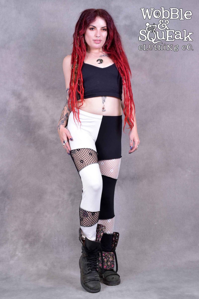 May include: Black and white leggings with a fishnet pattern. The leggings are split down the side, with one leg black and the other white. The model is wearing black boots.