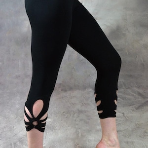 May include: Black cropped leggings with a unique floral cutout design at the ankles. The leggings are form-fitting and made of a stretchy material. The brand name "Wobble & Squeak Clothing Co." is visible in the upper right corner.