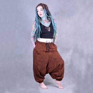 May include: Brown, loose-fitting,  harem pants with a drawstring waist. The pants are made of a soft, textured fabric.