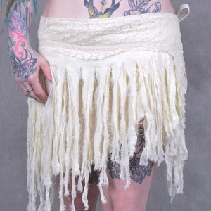A white, fringed skirt with a lace waistband. The skirt is made of a soft, flowing fabric and has a bohemian style.