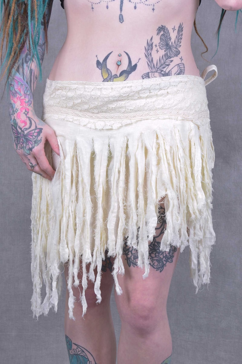 A white, fringed skirt with a lace waistband. The skirt is made of a soft, flowing fabric and has a bohemian style.