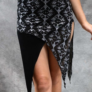 Puede incluir: Una falda de estampado blanco y negro con una abertura alta en el lateral. La falda está hecha de una tela transparente y tiene un panel de tela negra en la parte inferior.