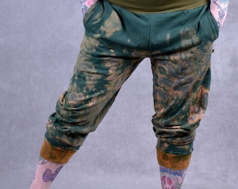 May include: Green and brown tie-dye pants with a wide green waistband. The pants are cuffed at the ankles and have a relaxed fit.