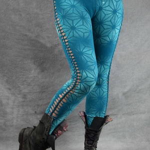 May include: Teal leggings with a geometric pattern and side cutouts. The leggings are worn with black boots.