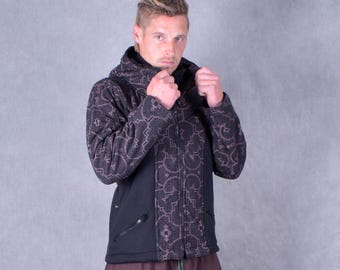 May include: A black hooded jacket with a geometric pattern in shades of brown and tan. The jacket has a zipper closure and side pockets. The model is wearing brown pants with green accents.