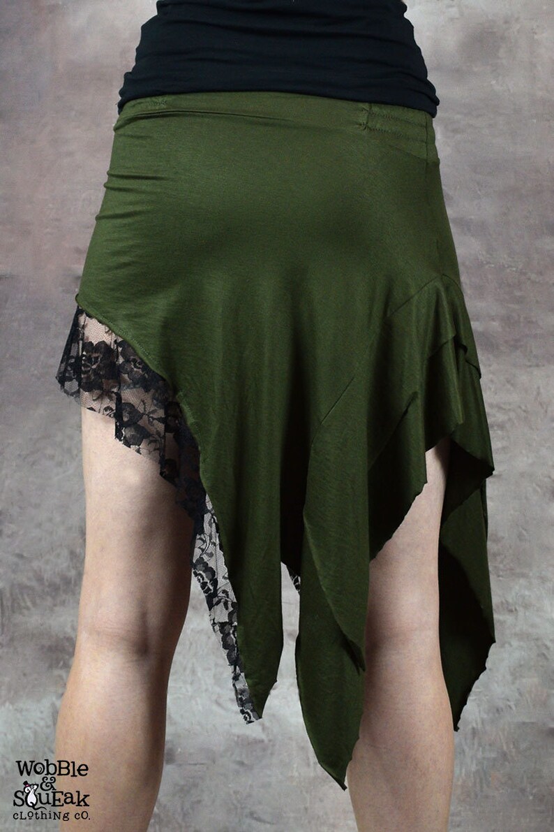 May include: A green asymmetrical skirt with black lace trim. The skirt is made of a soft, stretchy fabric and has a flowing, bohemian style.