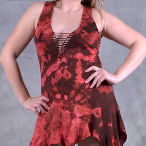 May include: A red and brown tie-dye sleeveless dress with a criss-cross detail at the neckline. The dress has a high-low hemline and is made of a soft, flowing fabric. "Wobble & Squeak Clothing Co."