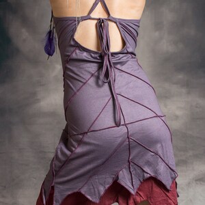 May include: A purple and burgundy dress with a criss-cross back and a unique leaf-shaped hemline. The dress is made of a soft, flowing fabric and has a relaxed fit.