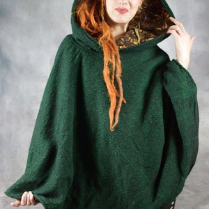 Puede incluir: Un poncho verde con capucha y forro floral negro y dorado. El poncho est&aacute; hecho de una tela suave y texturizada. "Wobble & SouEak Clothing Co." est&aacute; impreso en la etiqueta.
