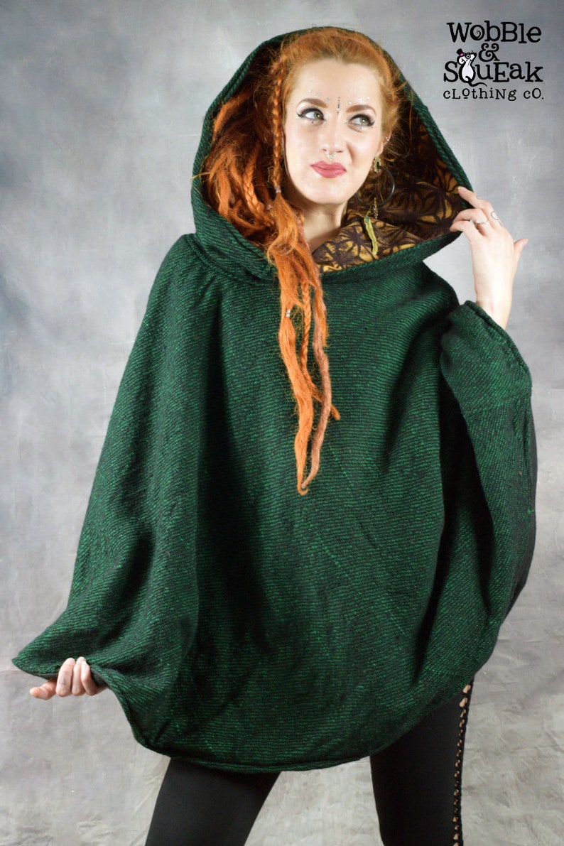 Puede incluir: Un poncho verde con capucha y forro floral negro y dorado. El poncho est&aacute; hecho de una tela suave y texturizada. "Wobble & SouEak Clothing Co." est&aacute; impreso en la etiqueta.