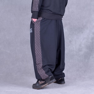 May include: Black sweatpants with a geometric pattern down the side. The sweatpants have a relaxed fit and a cuffed hem.