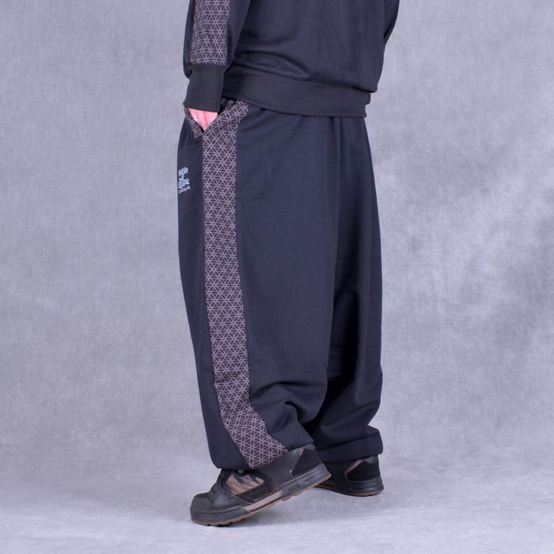 May include: Black sweatpants with a geometric pattern down the side. The sweatpants have a relaxed fit and a cuffed hem.
