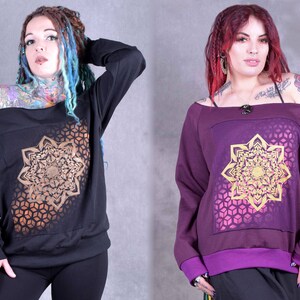 May include: Two off-the-shoulder sweatshirts with long sleeves and a geometric mandala design in gold on a black and purple background.