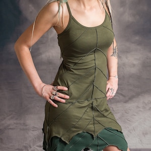May include: A green sleeveless dress with a leaf design. The dress has a fitted bodice and a flowing skirt. The model is wearing the dress with a silver necklace and earrings.