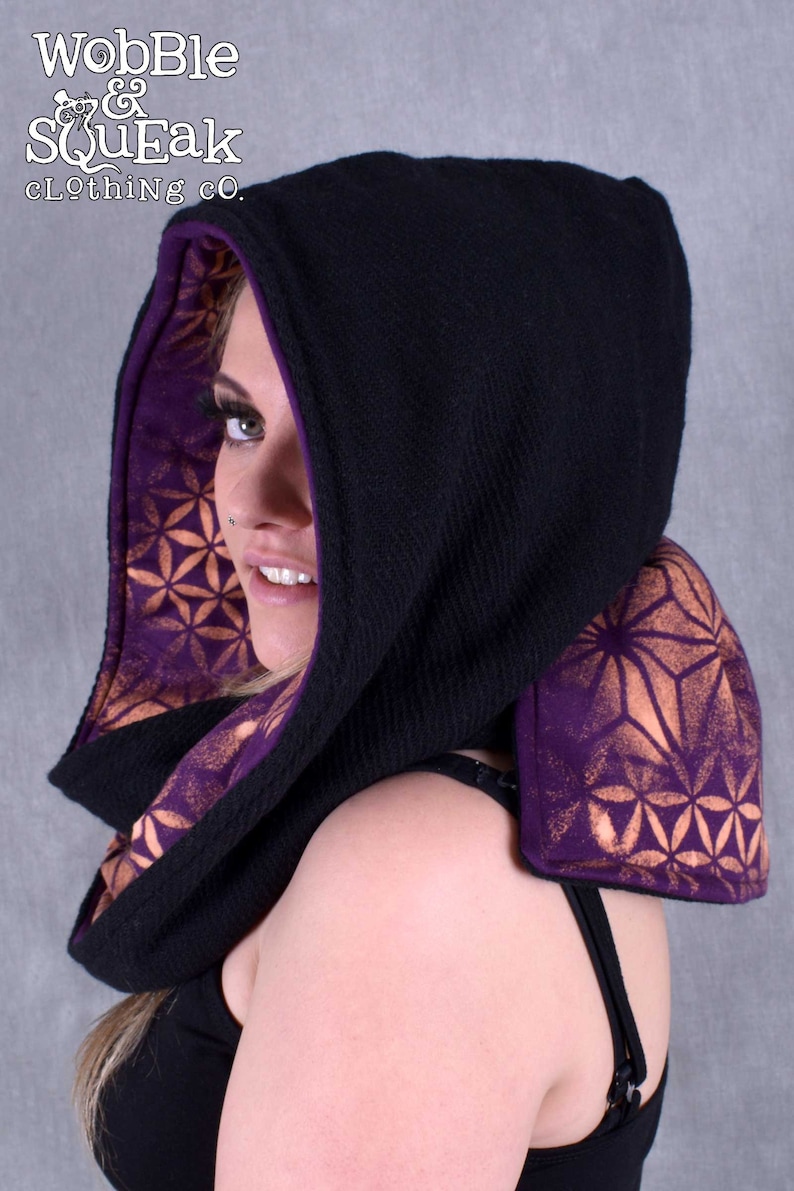May include: Black hooded scarf with a purple and gold geometric pattern lining. The scarf is made of a soft, warm fabric and is perfect for keeping warm in the winter.