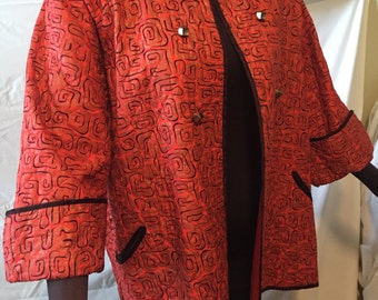 May include: A red quilted jacket with a black trim and a geometric pattern. The jacket has a mandarin collar and a button closure.