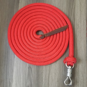 May include: Red rope dog lead with a brown leather handle and a silver hook.