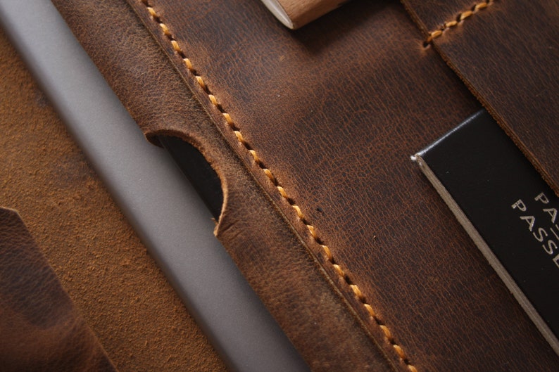 May include: Close-up of a brown leather travel wallet with a stitched edge and a black passport holder with the word "PASSE" visible.
