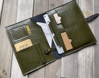 May include: A green leather portfolio with multiple pockets and slots for holding a tablet, phone, notepad, and pen. The portfolio has a flap closure and a strap with a buckle.
