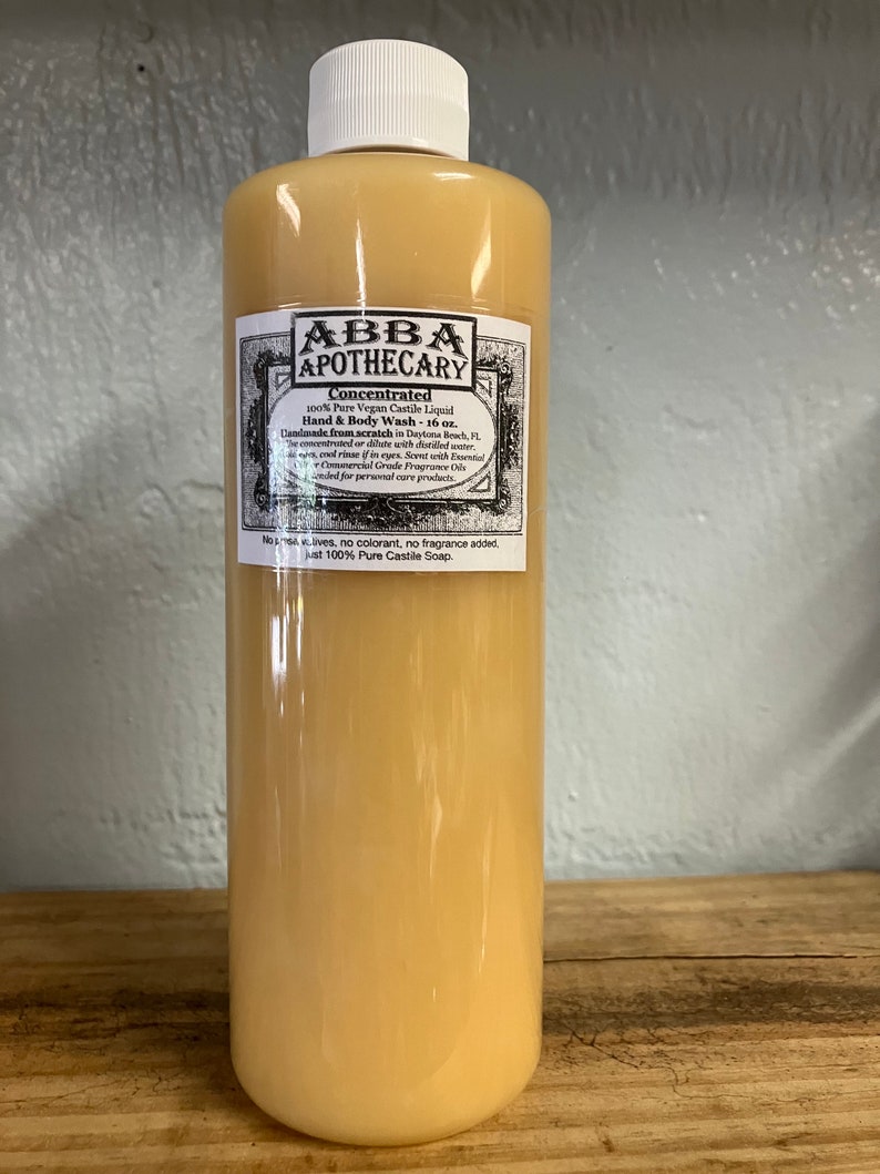 May include: A clear amber glass bottle with a white label that reads "ABBA APOTHECARY Concentrated 100% Pure Vegan Castile Liquid Hand & Body Wash - 16 oz. Handmade from scratch in Daytona Beach, FL. The concentrated or dilute with distilled water. Cool rinse if in eyes. Scent with Essential Oils, not Commercial Grade Fragrance Oils. Intended for personal care products. No additives, no colorant, no fragrance added, just 100% Pure Castile Soap."