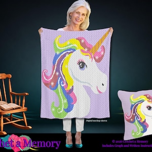 Può includere: Un modello all'uncinetto raffigurante un unicorno bianco con una criniera dai colori vivaci dell'arcobaleno e un corno dorato su uno sfondo viola chiaro. Il design è mostrato su una coperta rettangolare e un cuscino quadrato, con il testo Digital mockup shown.