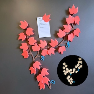 May include: A coral-coloured leaf and vine magnet set with a handwritten grocery list attached. The vine has small blue bead accents. A smaller, circular image shows a glowing version of the vine.