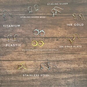 May include: Assortment of earring findings in various metals, including sterling silver, titanium, 14k gold, 18k gold plate, and stainless steel. The findings are displayed on a wooden surface.