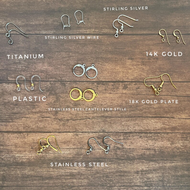 May include: Assortment of earring findings in various metals, including sterling silver, titanium, 14k gold, 18k gold plate, and stainless steel. The findings are displayed on a wooden surface.