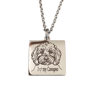 May include: Silver-toned necklace featuring a square pendant with an engraved Cavapoo dog design. The pendant includes the text "I ♡ my Cavapoo" below the dog's image. The necklace has a chain link design.