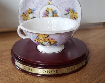 Cup and saucer set on display stand 2001 avon honor society award