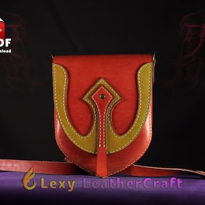 May include: A red leather crossbody bag with a yellow leather accent in the shape of a stylized arrow. The bag has a strap and a flap closure.
