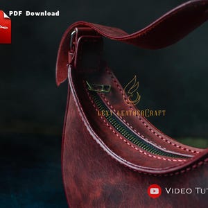 May include: Close-up of a burgundy leather handbag with a curved shape and a zipper closure. The bag has a strap and is stitched with a contrasting thread. The image includes the text "PDF Download" and "Video Tutorial".