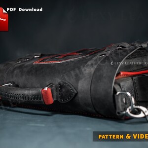 Puede incluir: Bolso de cuero negro con costuras rojas y un asa de cuero roja. El bolso tiene una hebilla de metal y una correa con un cierre de metal. El bolso est&aacute; sobre una superficie gris. "LEVY LEATHERCRAFT" est&aacute; impreso en el bolso.