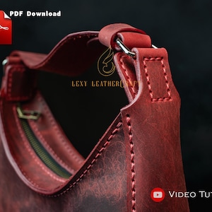May include: Close-up of a red leather handbag with a curved design. The bag features a zipper, a handle, and visible stitching. The image includes the text "PDF Download" and "Video Tutorial".