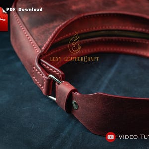 May include: A burgundy leather handbag with a curved design. The bag features a zipper closure and a strap with a silver-colored buckle. The text "PDF Download" and "Video Tutorial" are visible. The brand name "Lexy Leathercraft" is also visible.