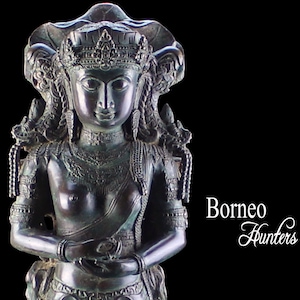 May include: A dark green bronze statue of a standing Buddha with a crown and multiple heads. The statue is on a pedestal with intricate carvings. The statue is about 20 inches tall.