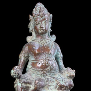 May include: A bronze statue of a seated deity with a crown and intricate details. The statue is on a pedestal with the inscription "Borneo Hunters".