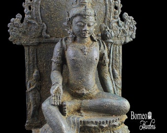 Puede incluir: Una estatua de bronce de una figura sentada con una corona, que lleva una túnica larga y está sentada en un trono con tallas intrincadas. La estatua está en posición sentada con las manos en un gesto de meditación. La estatua está sobre una base con un diseño decorativo.
