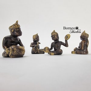 Può includere: Quattro piccole figurine di bronzo di persone che suonano strumenti musicali. Le figurine indossano abiti tradizionali e hanno dettagli intricati. Le figurine sono sedute su una superficie bianca.