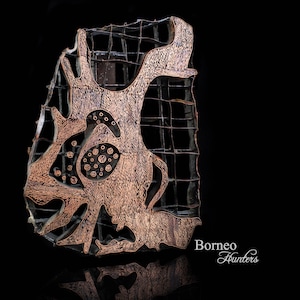 May include: A copper-coloured batik stamp with a geometric design. The stamp is made of wood and has a grid pattern. The text "Borneo Hunters" is visible in the lower right corner of the image.