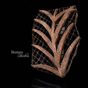 May include: A wooden printing block with a carved design of a stylised leaf pattern. The block is brown and has a grid pattern.