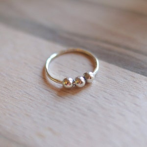 May include: A silver ring with three round beads.