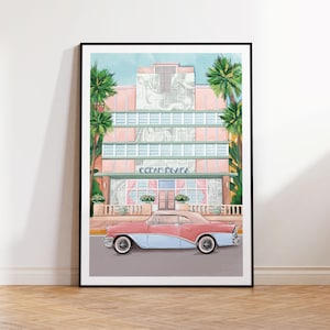 May include: A pink and blue vintage car parked in front of a pastel pink and green art deco building with palm trees. The building has the text "Ocean Plaza" above the entrance.