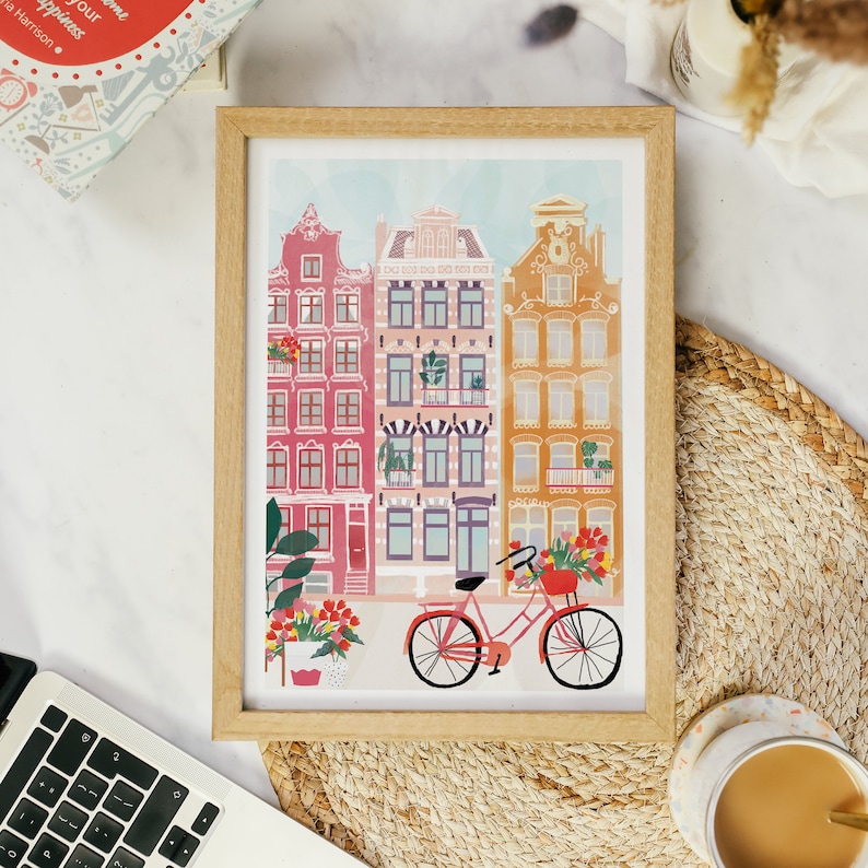 Puede incluir: Una ilustraci&oacute;n enmarcada de edificios coloridos con una bicicleta roja en frente. Los edificios tienen acentos rojos, amarillos y blancos. La bicicleta tiene una cesta con flores.
