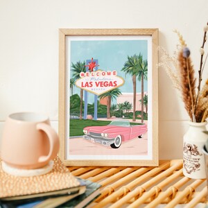 May include: A framed illustration of a pink convertible driving past the iconic "Welcome to Fabulous Las Vegas" sign with palm trees in the background.